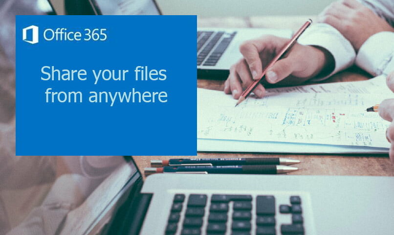 A man writing on a paper beside two laptops